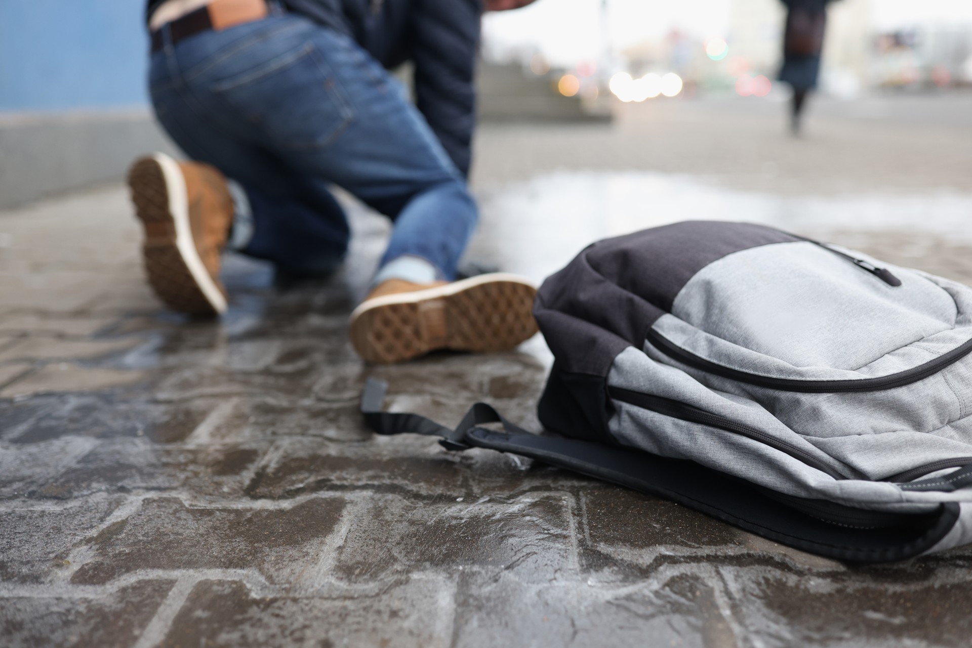 Man with backpack felling on slippery sidewalk in winter closeup